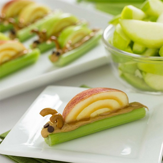 celery stick, peanut butter, and an apple snack shaped in the form of a snail