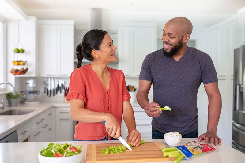 picture of a couple in a kitchen chopping celery